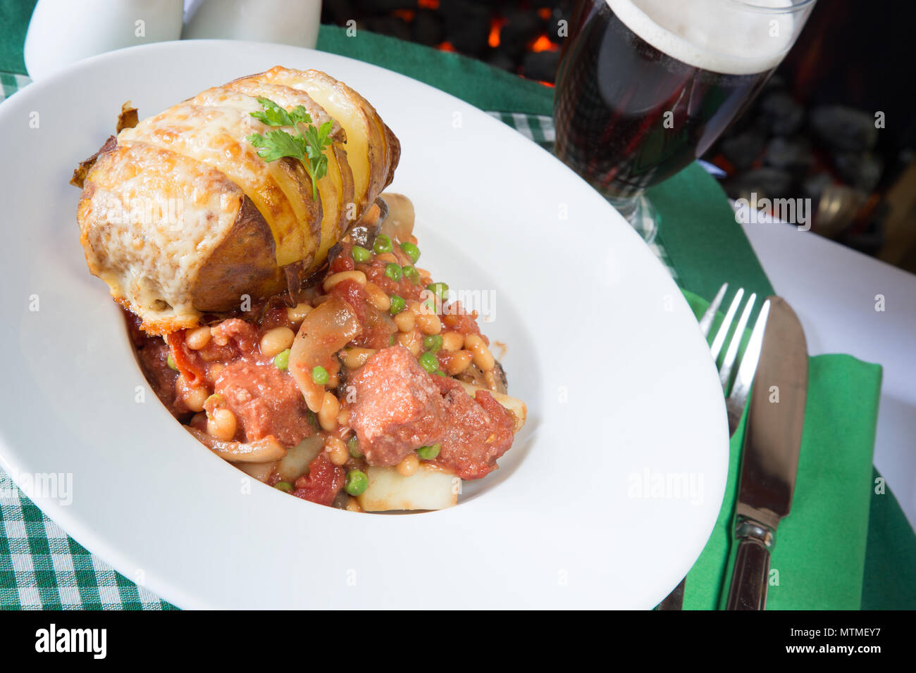 Une partie de Corned Beef hash servi avec un fromage surmontée de pommes de terre Hasselback Banque D'Images