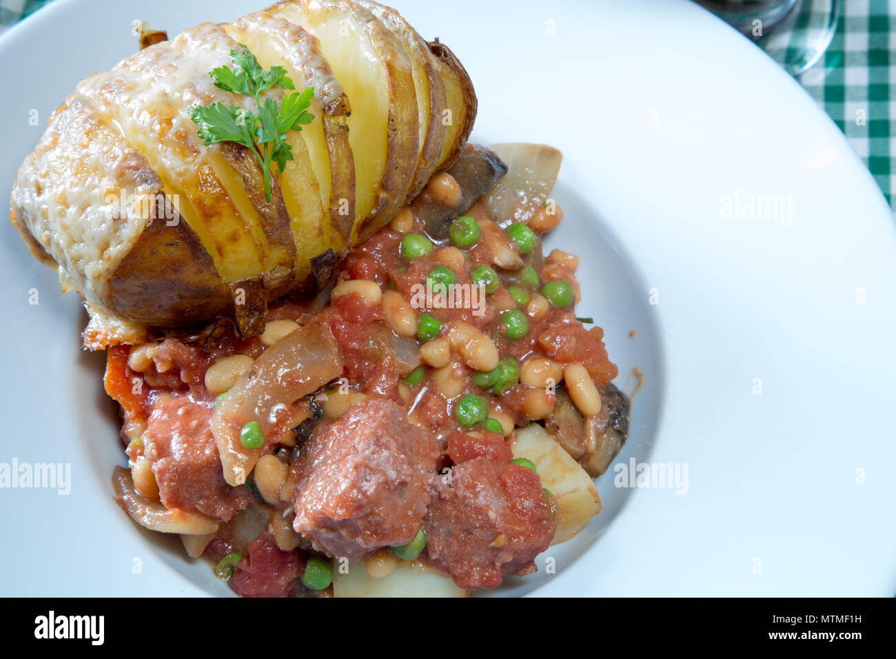 Une partie de Corned Beef hash servi avec un fromage surmontée de pommes de terre Hasselback Banque D'Images