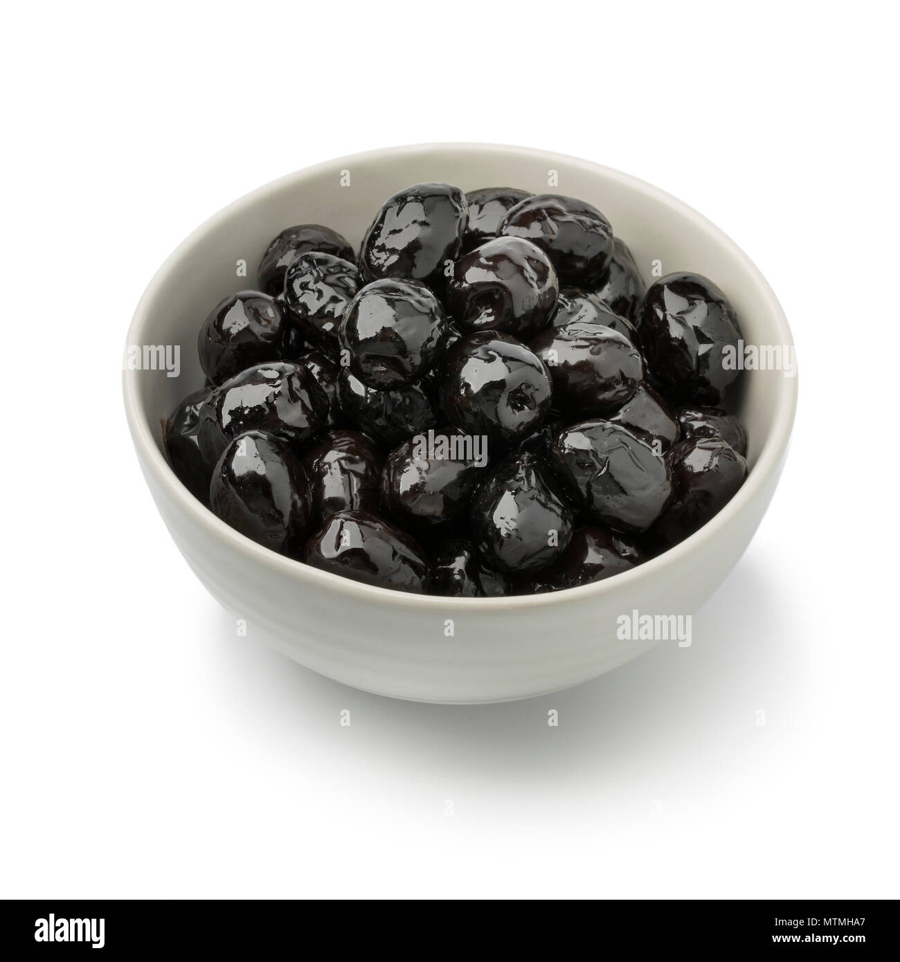 Bol d'olives noires brillantes comme collation isolé sur fond blanc Banque D'Images