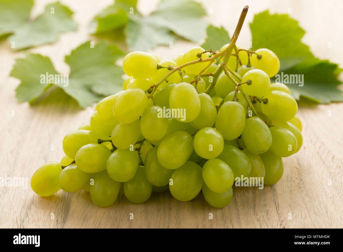 Tas de raisins verts frais avec des feuilles de vigne sur l'arrière-plan Banque D'Images