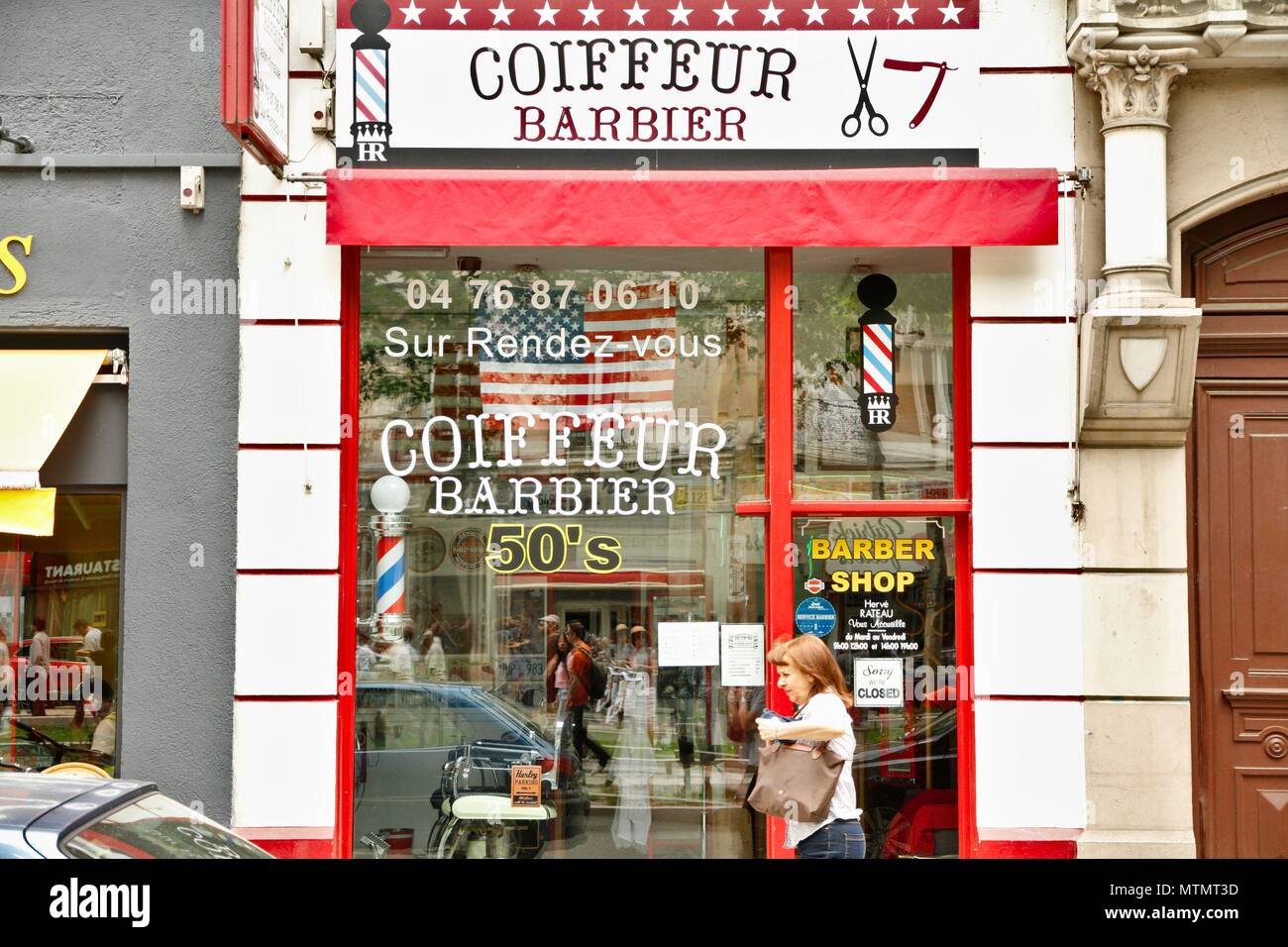 Salon de coiffure avec un Américain, USA, d'une décoration et d'un vieux signe. Renouvellement des barbiers en France grâce à une clientèle de personnes branchées. Grenoble, Isère Banque D'Images