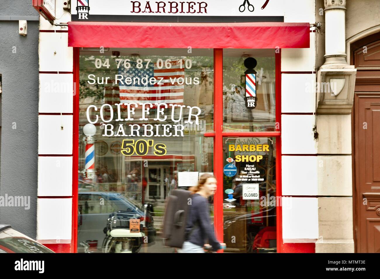 Salon de coiffure avec un Américain, USA, d'une décoration et d'un vieux signe. Renouvellement des barbiers en France grâce à une clientèle de personnes branchées. Grenoble, Isère Banque D'Images