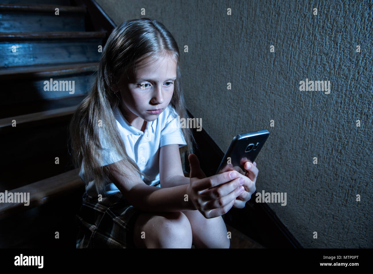 Déprimé triste jeune fille victime de cyberintimidation par smart mobile phone sitting on stairs vous sentir seul, malheureux, sans espoir et d'abus. Intimidé par texte Banque D'Images
