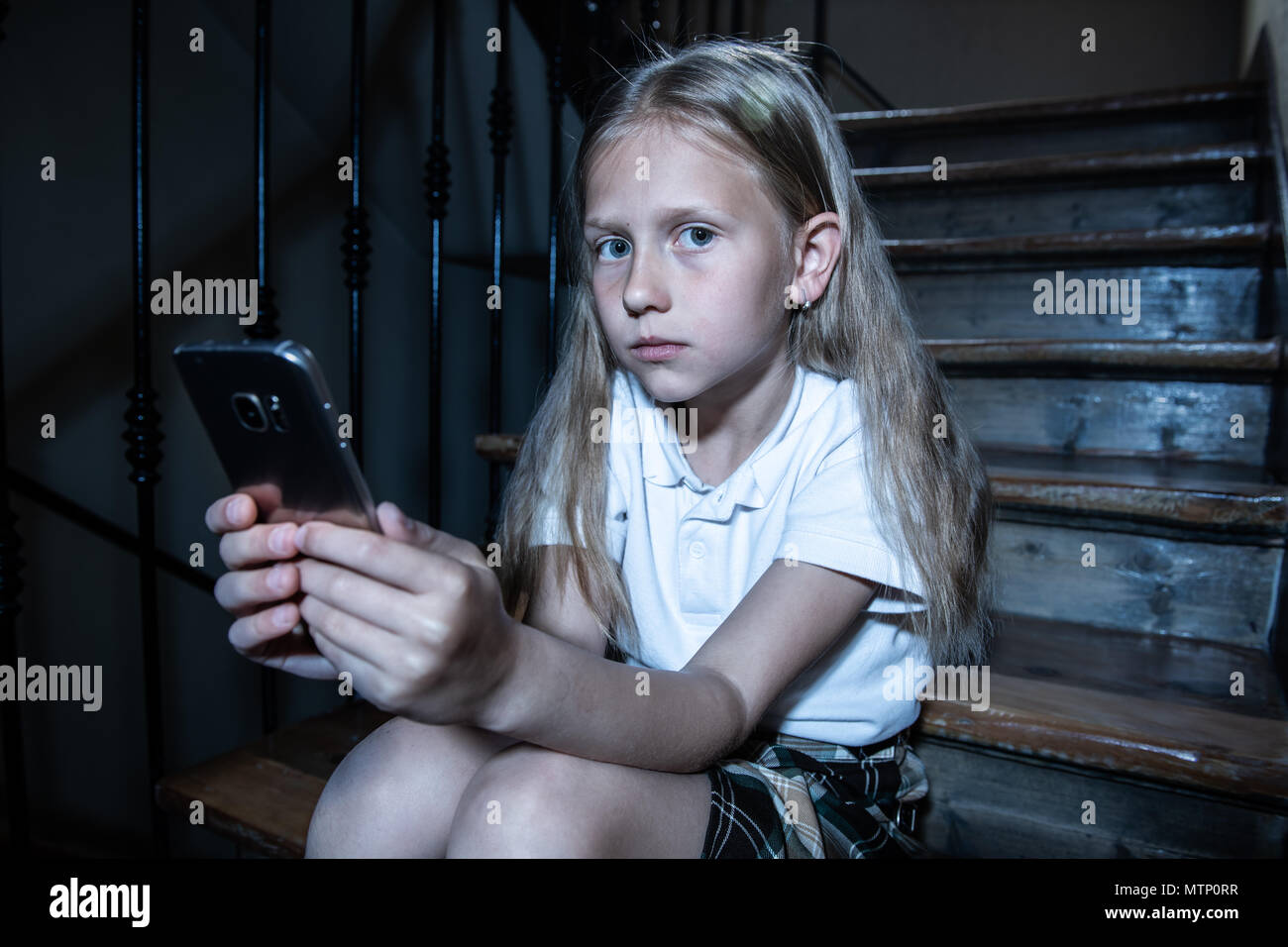 Déprimé triste jeune fille victime de cyberintimidation par smart mobile phone sitting on stairs vous sentir seul, malheureux, sans espoir et d'abus. Intimidé par texte Banque D'Images