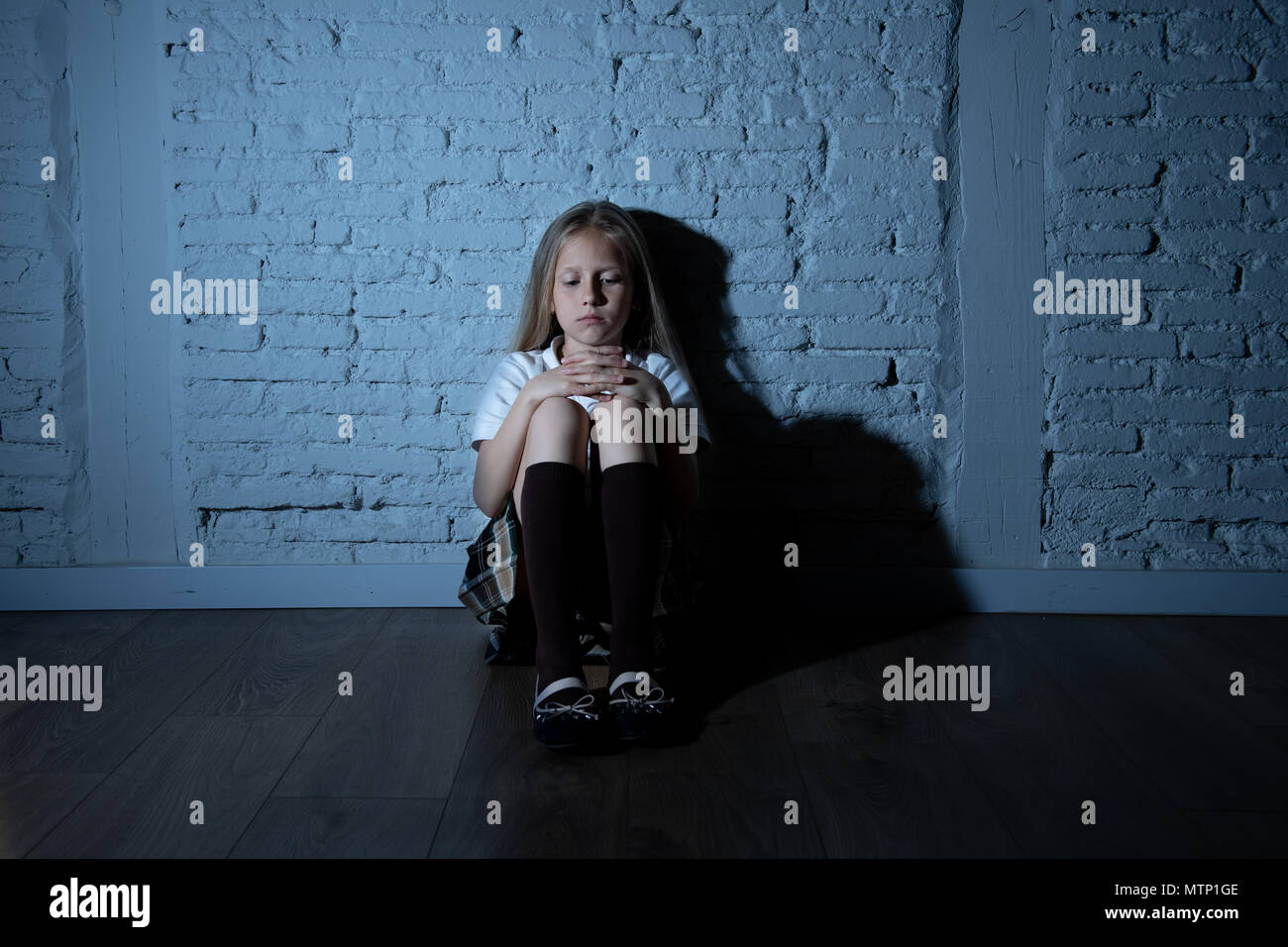 Désespérément triste jeune fille souffrant de bulling et abattage harcèlement seul, malheureux et sans espoir désespéré assis contre le mur, Lumière sombre. Sc Banque D'Images