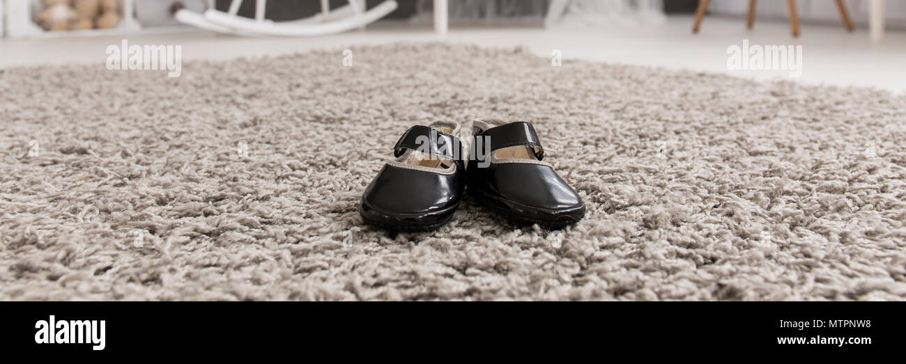 Close-up of newborn girl's shoes sur un tapis beige moelleux dans une chambre de bébé lumineux Banque D'Images