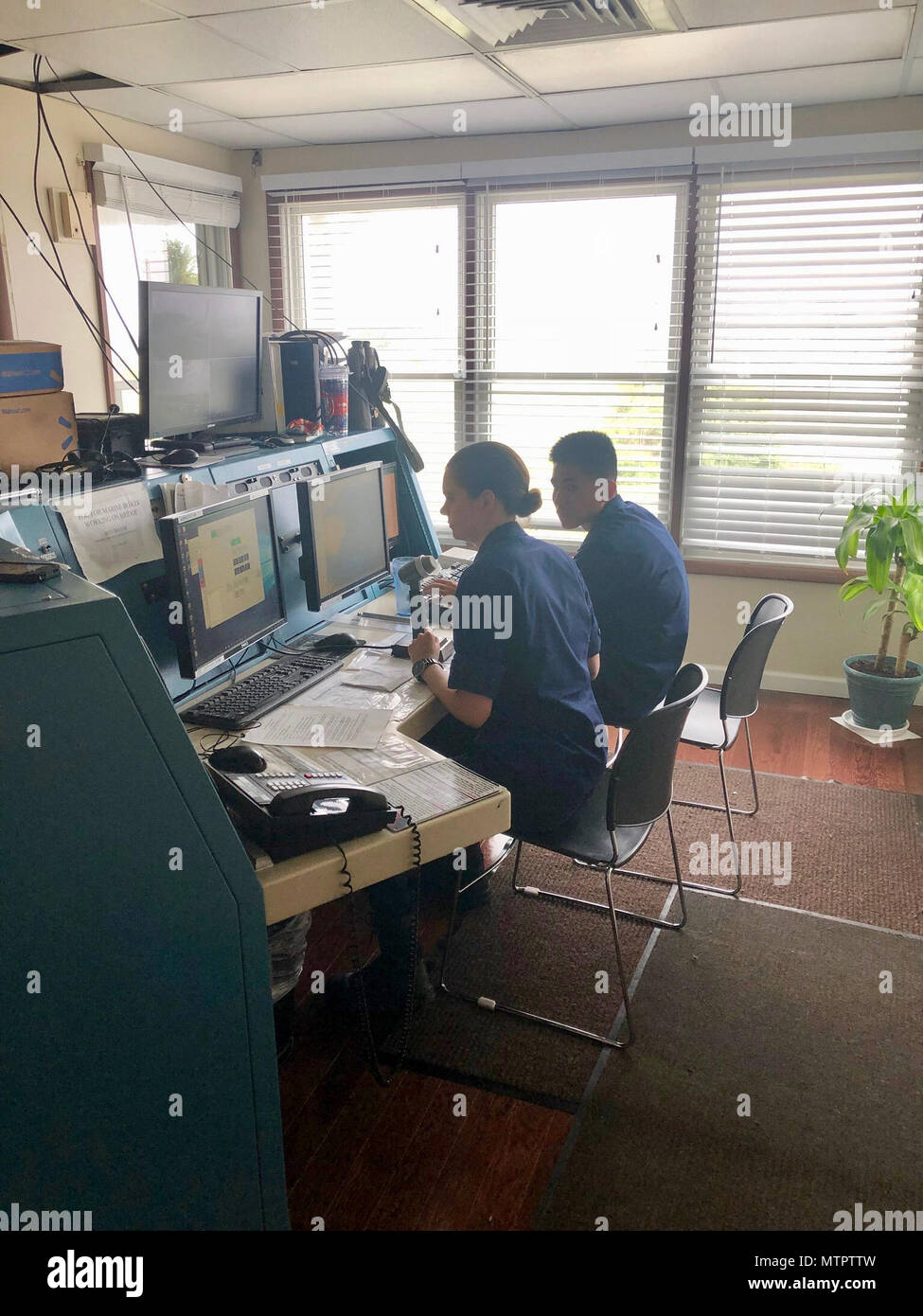 Auxiliarist La Garde côtière Caroline Howard et Seaman Khoi Vu, de quart à la Station Oregon Inlet à Nags Head, Caroline du Nord, aider à coordonner un cas de recherche et sauvetage de la station, en chambre, regarder des communications, le 22 mai 2018. Un moteur de 47 pieds bateau la vie de l'équipage de la station a lancé après avoir reçu la notification d'une pêche récréative de 28 pieds bateau prenait l'eau à 35 km au sud-est de l'Oregon Inlet. (U.S. Photo de la Garde côtière canadienne par le Premier maître de James Laird/libérés) Banque D'Images