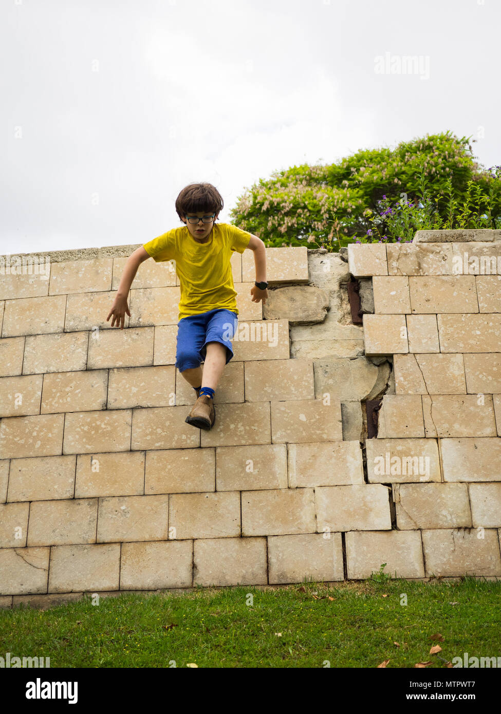 Jeune garçon de dix saute un mur. Humpty Dumpty sat on a wall, Humpty Dumpty avait une grande chute tous les chevaux du roi et tous les hommes du roi n'a pas p Banque D'Images