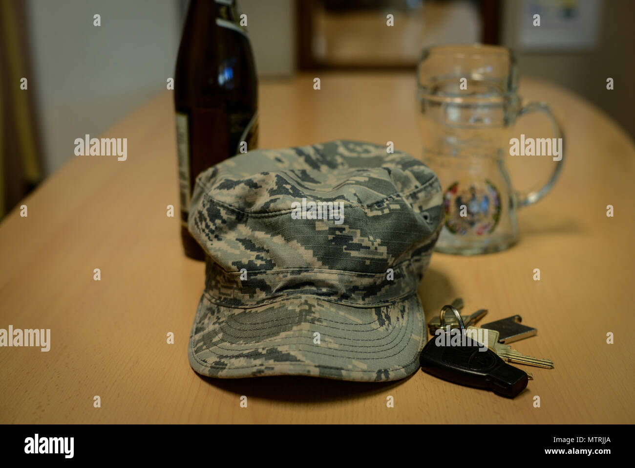 Une bataille à motifs uniforme froissé d'un membre de la cap se trouve sur une table à côté d'une bouteille de bière , jeu de clés, et beer mug à base aérienne de Ramstein, en Allemagne, le 20 janvier 2017. L'Airman contre l'alcool au volant programme est disponible dans de nombreuses bases de l'Armée de l'air et vise à prévenir les cas de DUI chez les aviateurs. (U.S. Photo par la force d'un membre de la 1re classe Joshua Magbanua) Banque D'Images