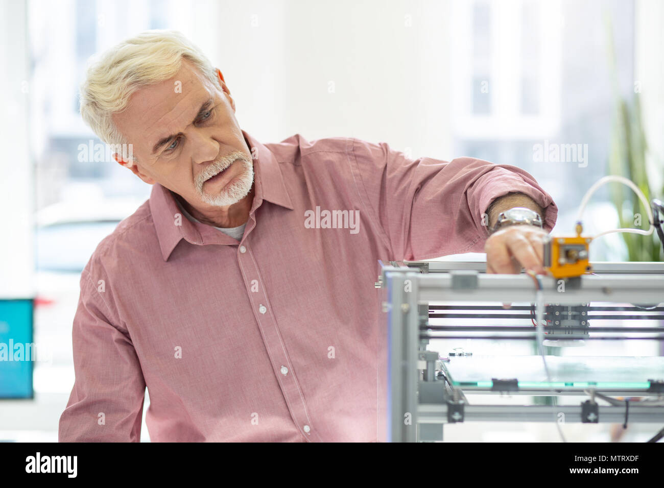 Vieil homme agréable en utilisant l'imprimante 3D au bureau Banque D'Images