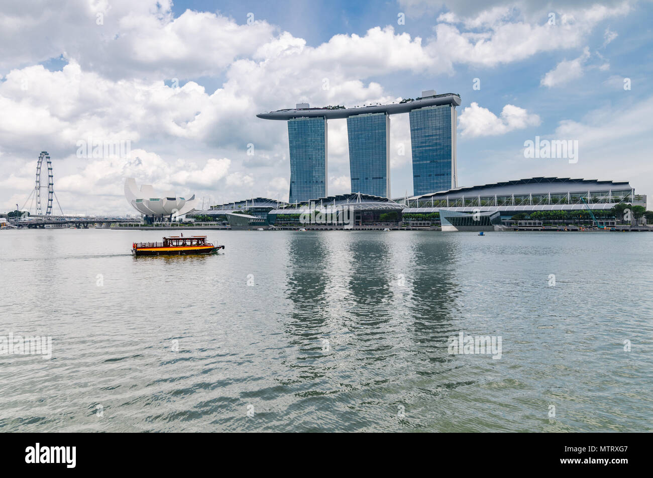 Un bateau de croisière connu comme twakows ride passer la célèbre Marina Bay Sands Hotel. Le bateau ont été utilisés à des fins de transport le long de la rivière Singapour. Banque D'Images