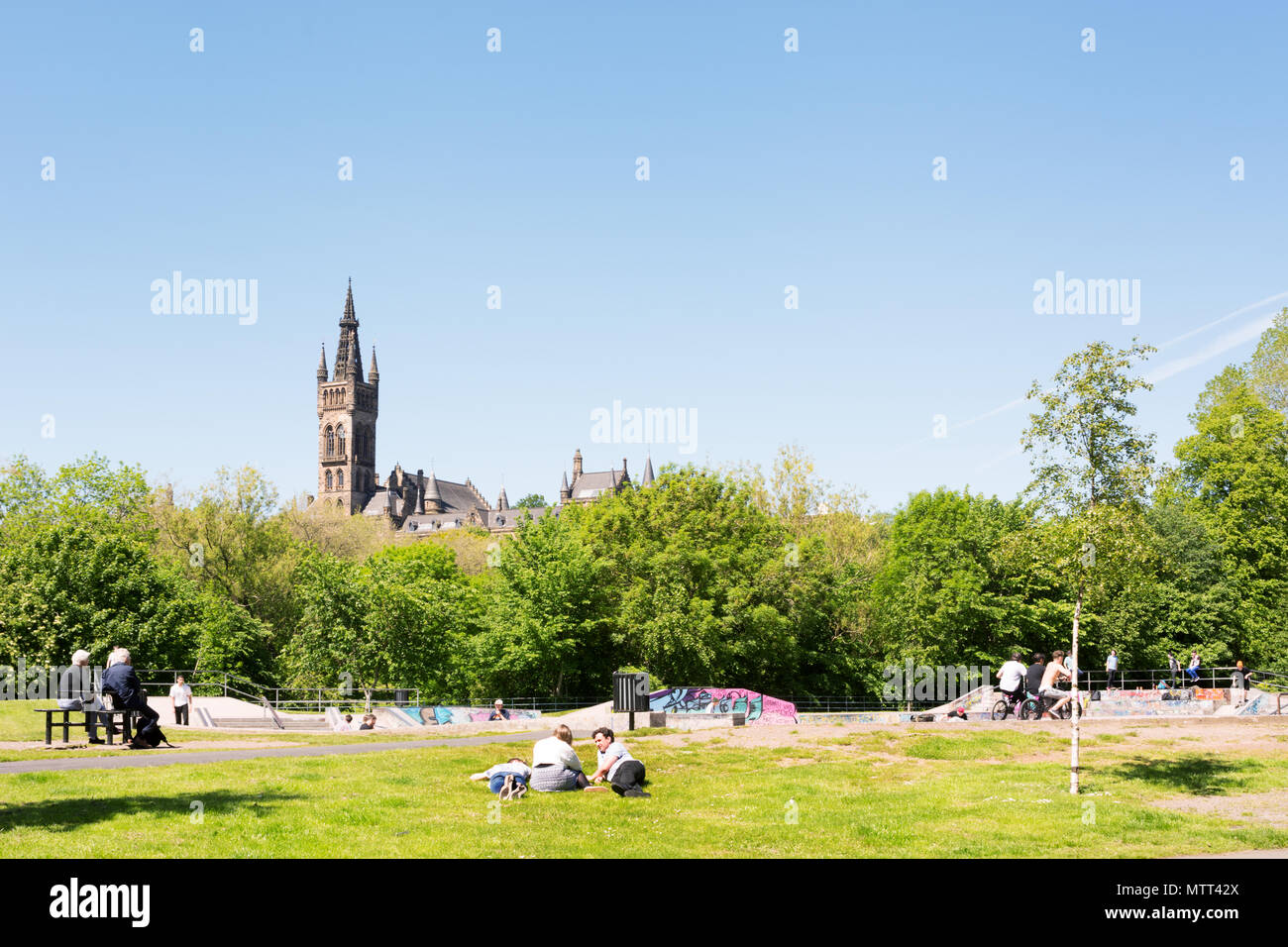 Les personnes bénéficiant d'une chaude journée ensoleillée sur les pelouses du parc de Kelvingrove, Kelvingrove Art Gallery and Museum de l'arrière-plan Banque D'Images