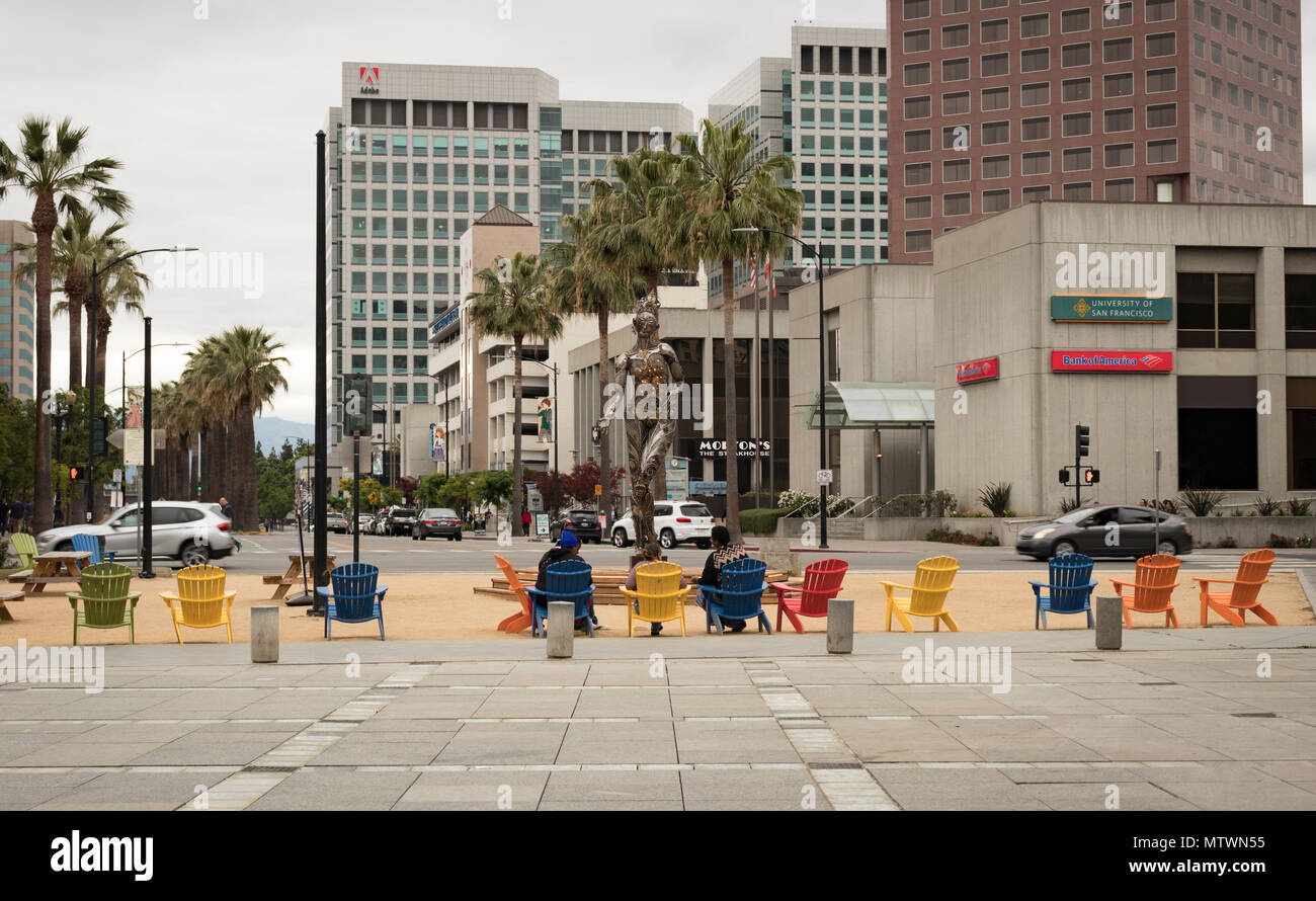 San José, Californie, Etats-Unis - 28 mai 2018: Les gens se prélasser dans des chaises Adirondack colorées au parc Plaza de Cesar Chavez, avec une vue sur Adobe Systems. Banque D'Images