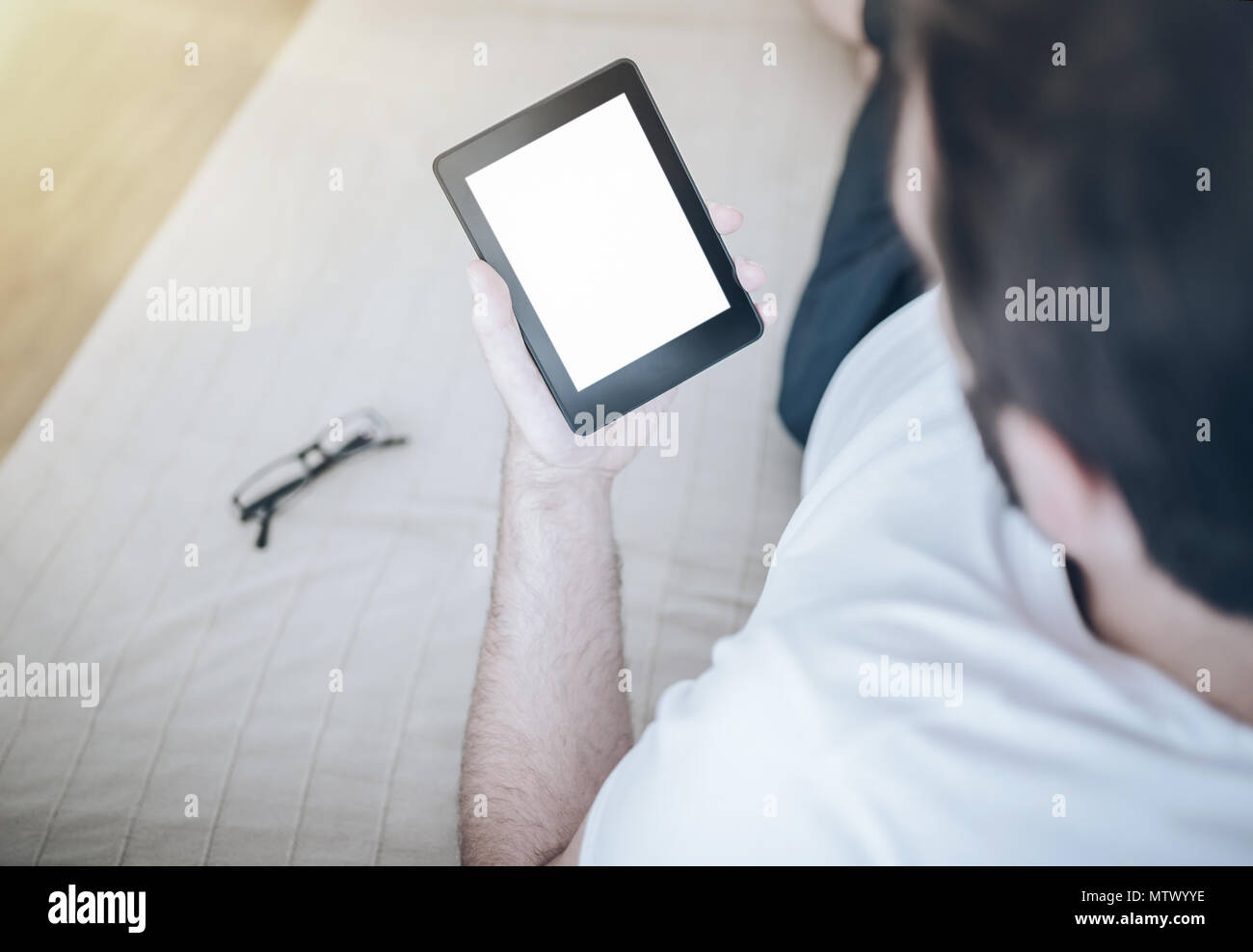 Man relaxing on couch using e-Book Reader ou une tablette ordinateur Banque D'Images