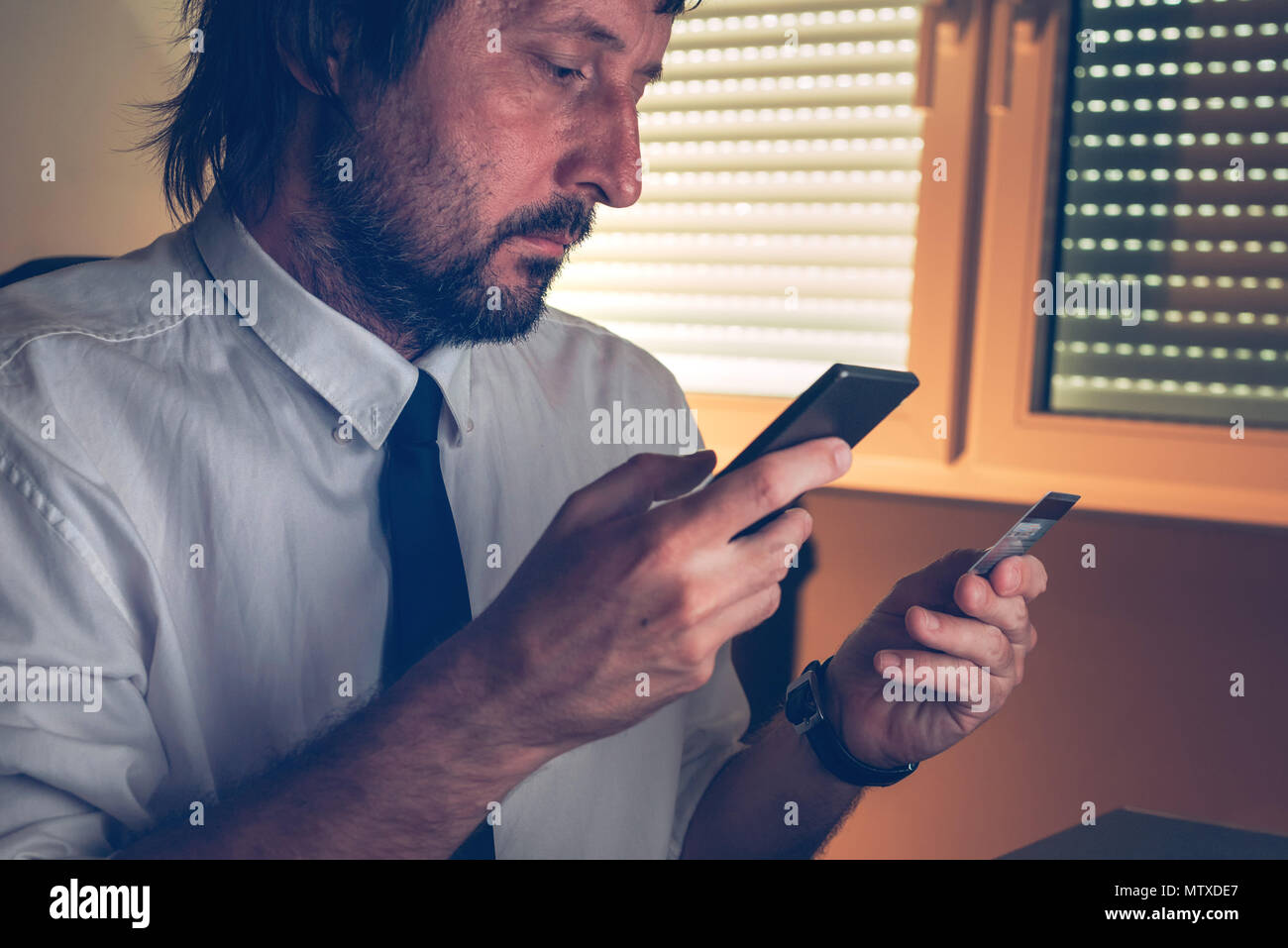 Portrait des services bancaires mobiles application pour acheter en ligne avec carte de crédit et à l'intérieur du smartphone bureau sombre, selective focus Banque D'Images