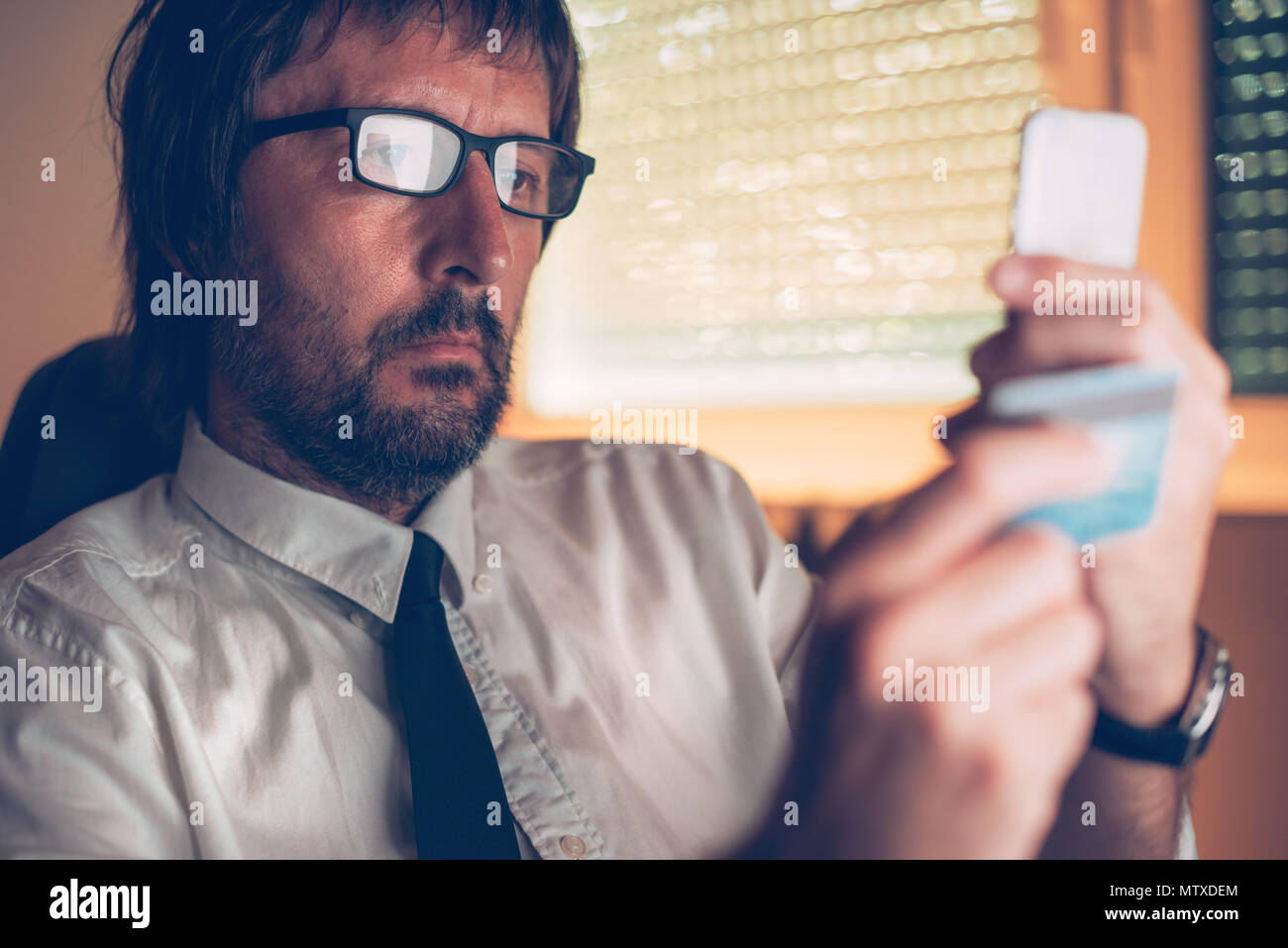 Portrait des services bancaires mobiles application pour acheter en ligne avec carte de crédit et à l'intérieur du smartphone bureau sombre, selective focus Banque D'Images