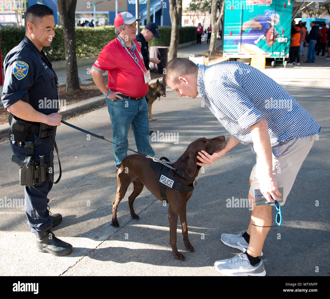 Un officier de police de San Francisco présente son K-9 à un ventilateur au vert découverte au centre-ville de Houston, le 31 janvier 2017. Les organismes d'application de la loi de l'autre côté du pays et territoires des États-Unis se sont réunis pour fournir un environnement sûr pour les fans de l'événement et des mécènes de Super Bowl 51. U.S. Coast Guard photo de Maître de 3e classe Dustin R. Williams Banque D'Images