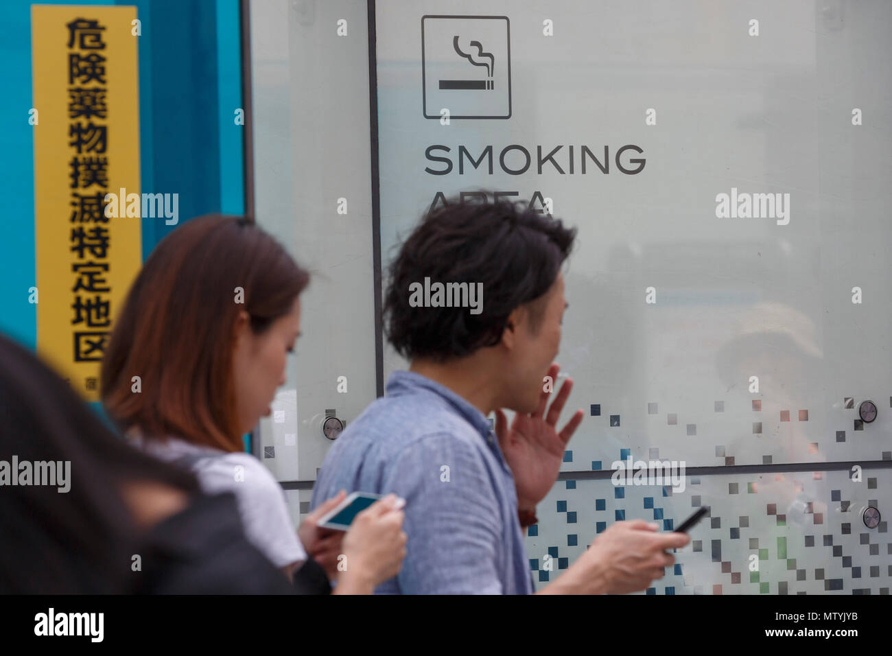 Un homme fume dans un espace fumeurs à l'extérieur de la gare de Shinjuku, le 31 mai 2018, Tokyo, Japon. L'Organisation mondiale de la Santé (OMS) et le ministère de la santé continuent de pousser ''tabac'' visant à interdire de fumer dans tous les lieux publics avant les Jeux Olympiques de 2020, mais les efforts ont échoué à ce jour. Credit : Rodrigo Reyes Marin/AFLO/Alamy Live News Banque D'Images