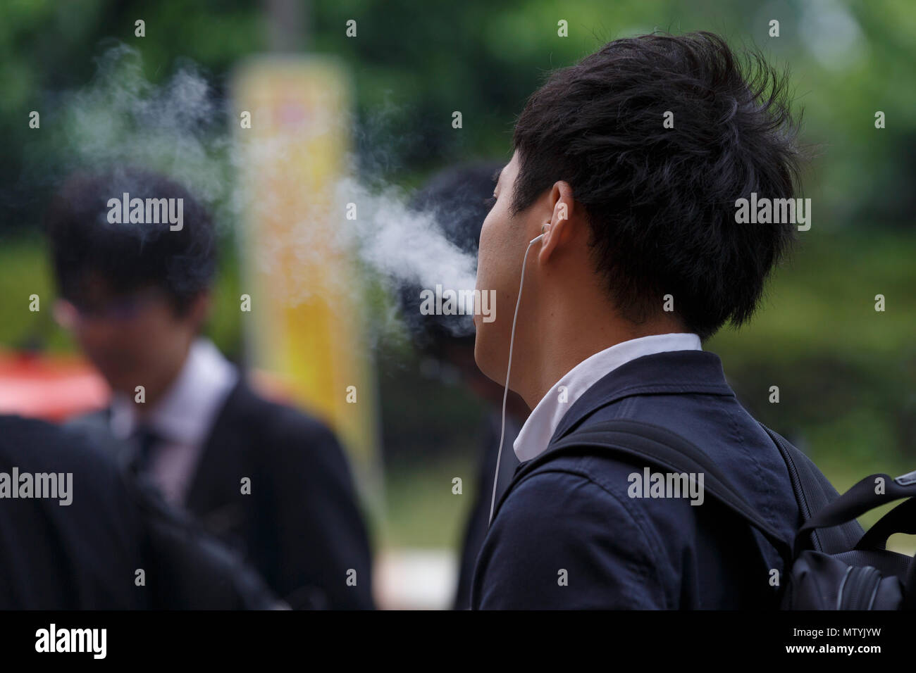 Un homme fume dans un espace fumeurs à l'extérieur de la gare de Shinjuku, le 31 mai 2018, Tokyo, Japon. L'Organisation mondiale de la Santé (OMS) et le ministère de la santé continuent de pousser ''tabac'' visant à interdire de fumer dans tous les lieux publics avant les Jeux Olympiques de 2020, mais les efforts ont échoué à ce jour. Credit : Rodrigo Reyes Marin/AFLO/Alamy Live News Banque D'Images