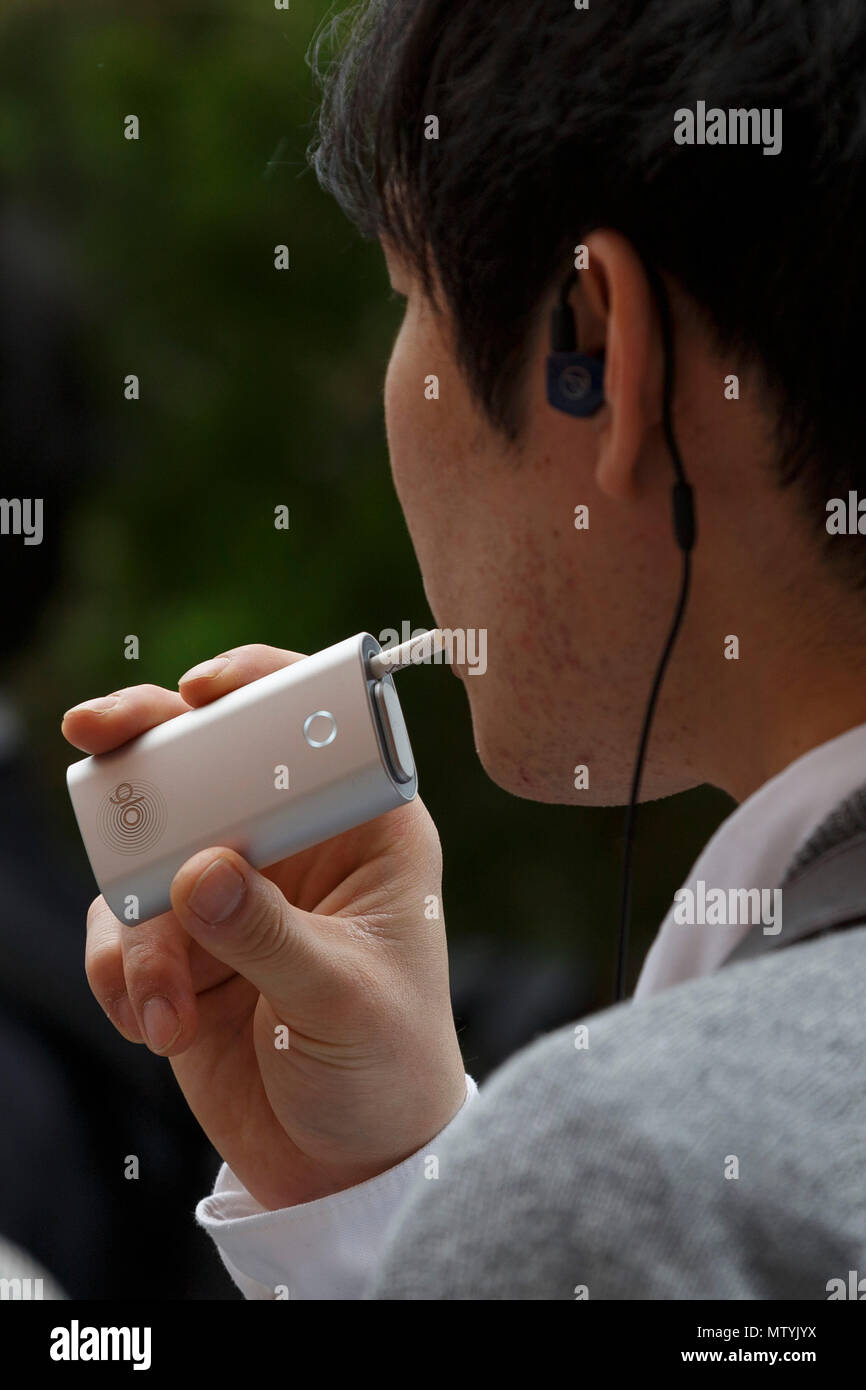Un homme fume dans un espace fumeurs à l'extérieur de la gare de Shinjuku, le 31 mai 2018, Tokyo, Japon. L'Organisation mondiale de la Santé (OMS) et le ministère de la santé continuent de pousser ''tabac'' visant à interdire de fumer dans tous les lieux publics avant les Jeux Olympiques de 2020, mais les efforts ont échoué à ce jour. Credit : Rodrigo Reyes Marin/AFLO/Alamy Live News Banque D'Images