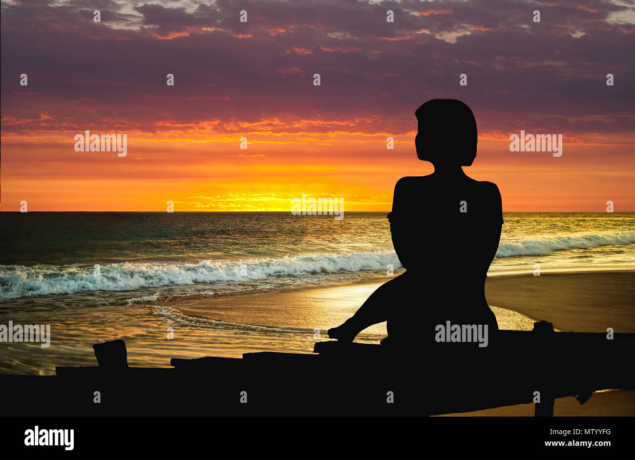 Silhouette d'une femme assise sur un quai à au coucher du soleil Banque D'Images