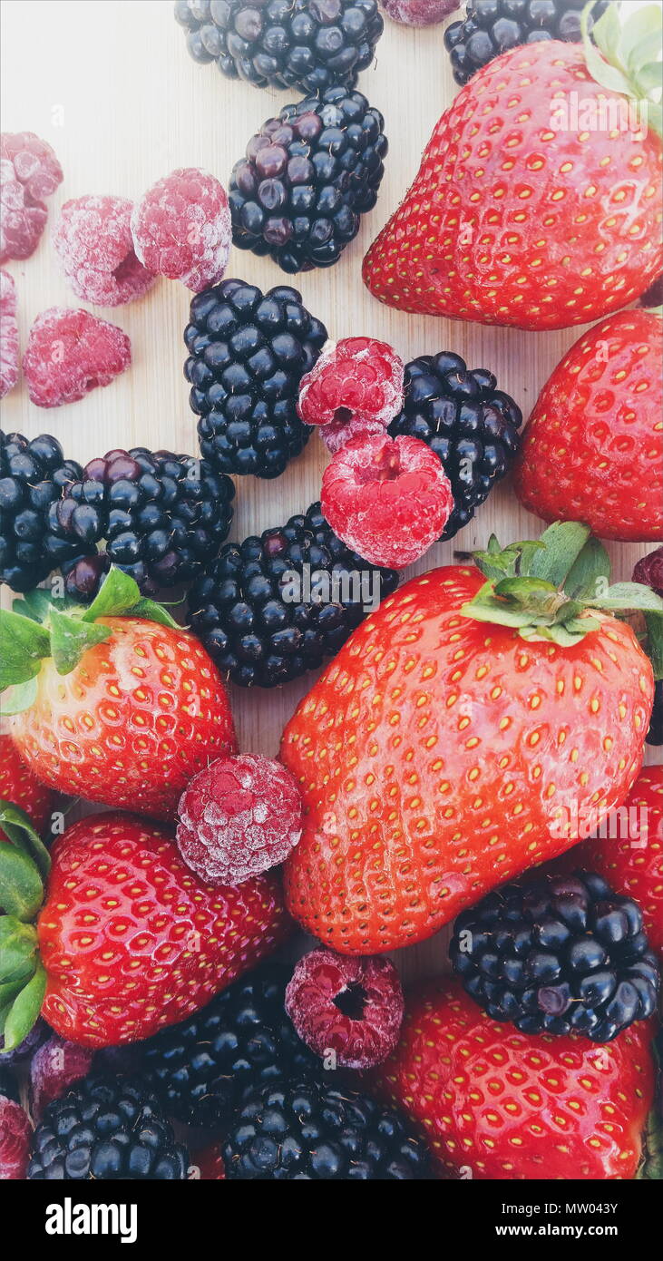 Les fraises, mûres et framboises sur une planche à découper Banque D'Images