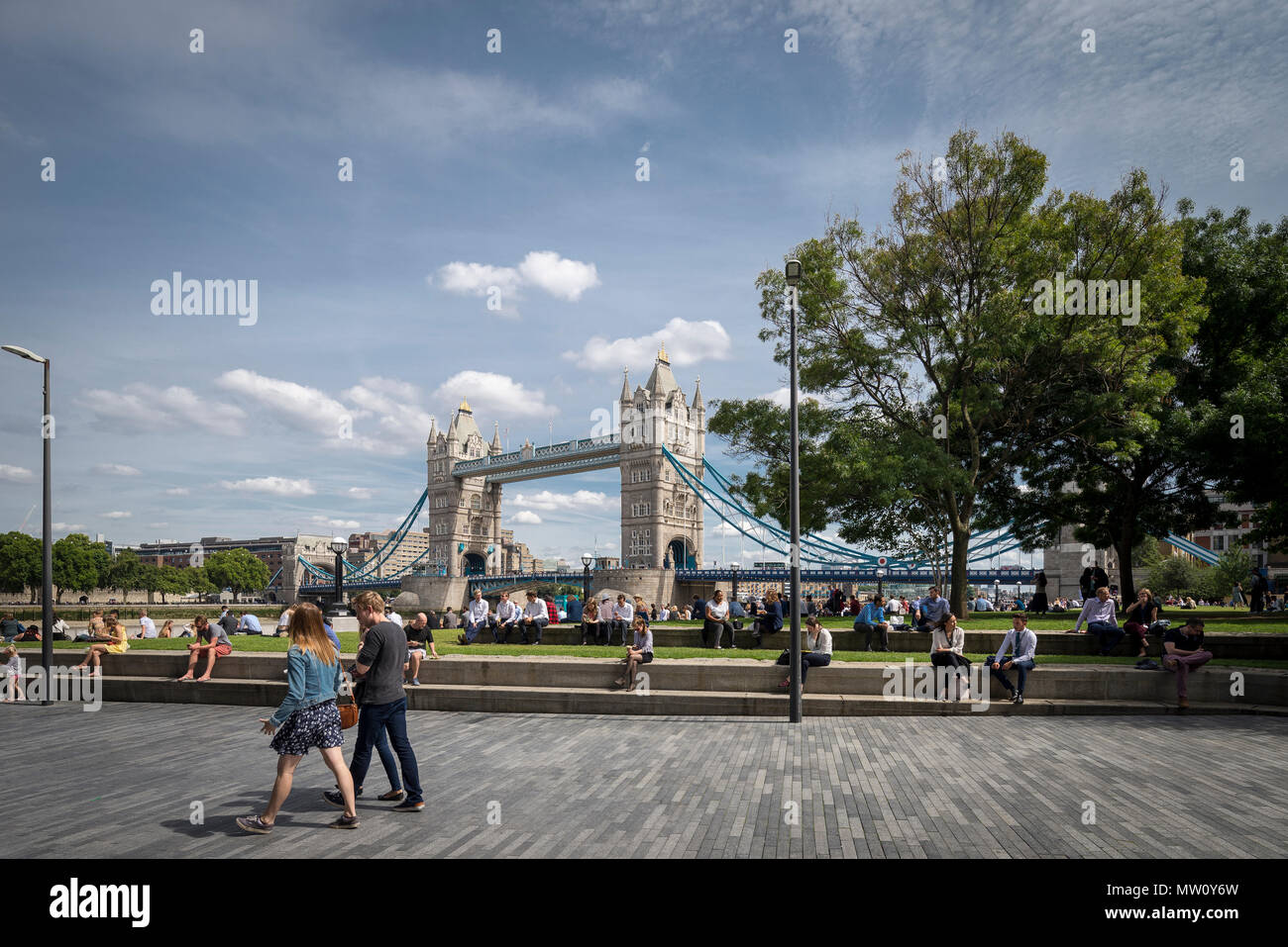 Heure du déjeuner à Potters Fields Park, c'est la ville de Londres. Le soleil brille alors que les collègues de travail pique-niquent sur l'herbe avec Tower Bridge en arrière-plan Banque D'Images