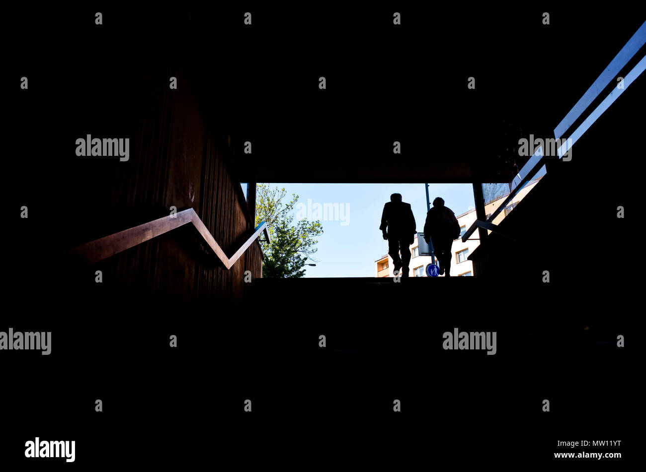 Couple en silhouette à la fin d'un escalier, sortant par un passage inférieur Banque D'Images