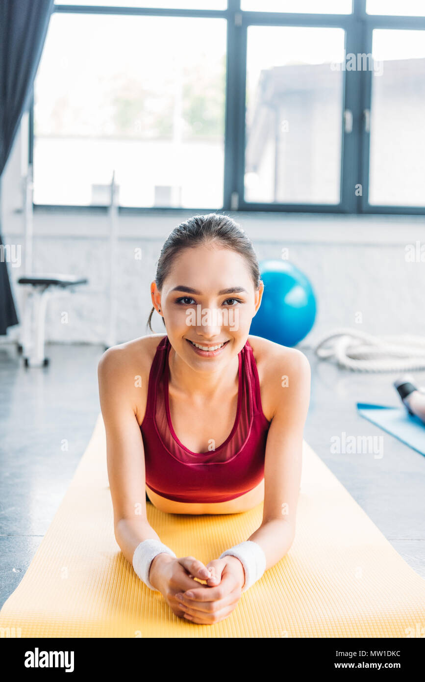 Smiling asian de la sportive en tapis de sol fitness sur bracelets at gym Banque D'Images
