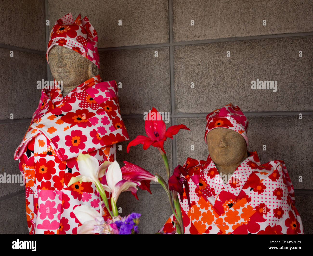 Statues bouddhistes, à un culte, vêtu en tissu à motifs, avec des offres de fleurs, Shikoku, Takamatsu, Japon Banque D'Images