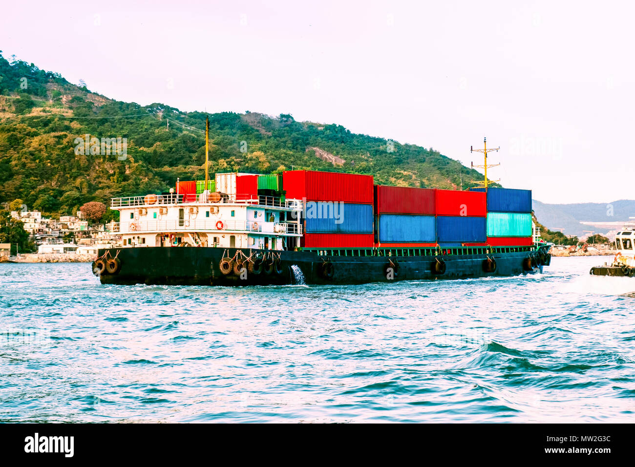 Gros bateau nautique dans le port de Victoria, Hong Kong au coucher du soleil. Logistique d'entreprise, l'importation, l'exportation concept. Mer de Chine du Sud, l'océan Pacifique. Banque D'Images