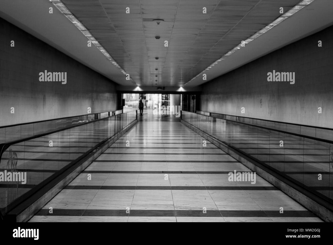 Photo en noir et blanc de la gare avec longue marche avec escaliers mécaniques horizontales Banque D'Images