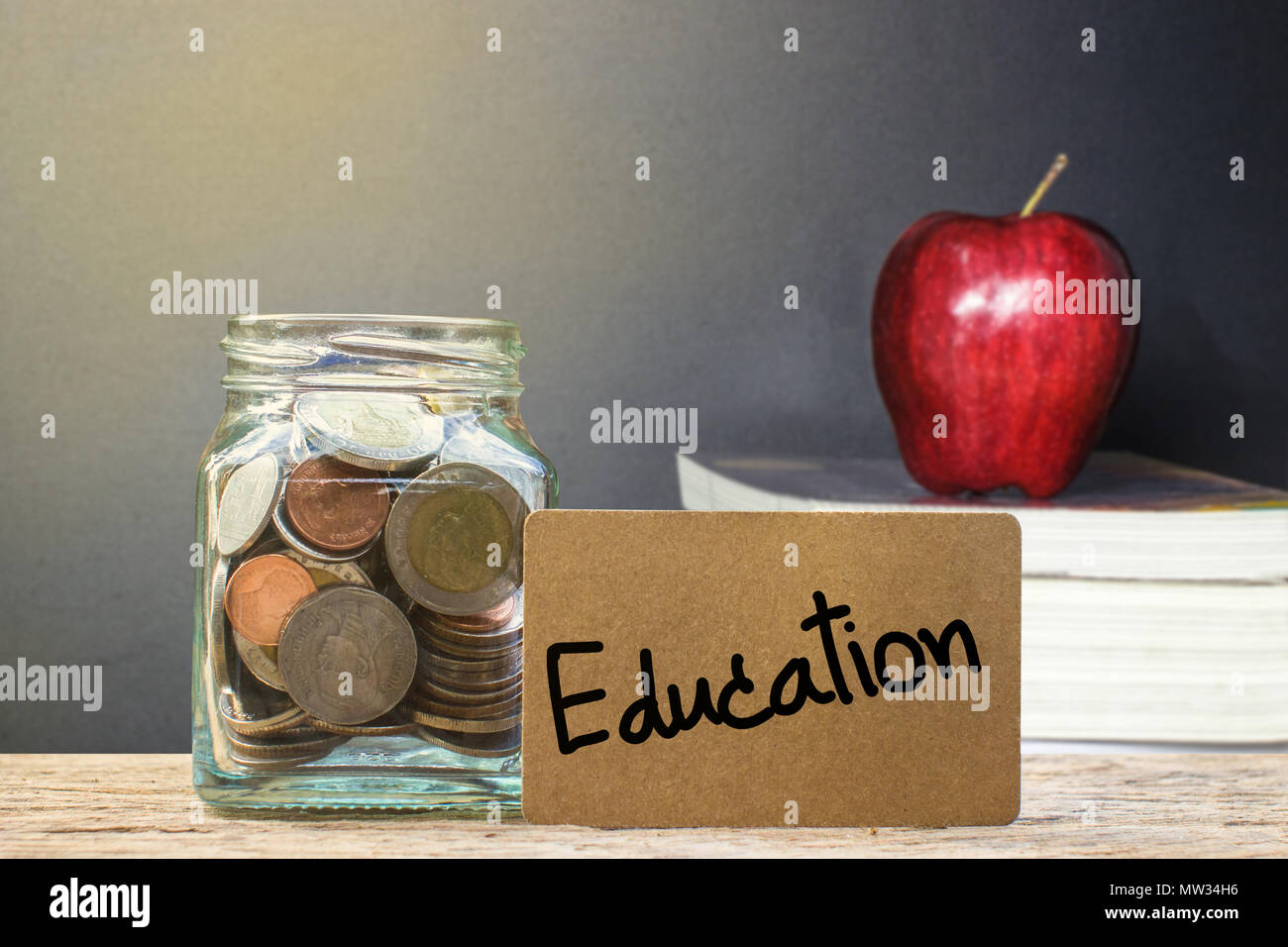 L'argent d'économie conceptuelle pour l'éducation avec pomme rouge floue sur les livres avec la lumière comme arrière-plan. Banque D'Images