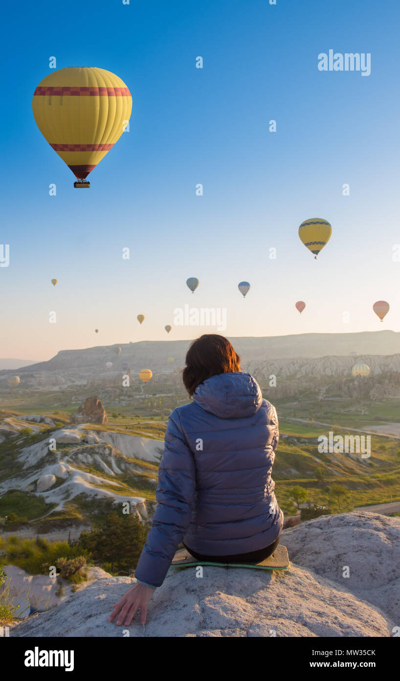 Femme sur le dessus de la Cappadoce hill en lever tôt le matin, lorsque ballons volent. La Cappadoce, Turquie scène romantique Banque D'Images