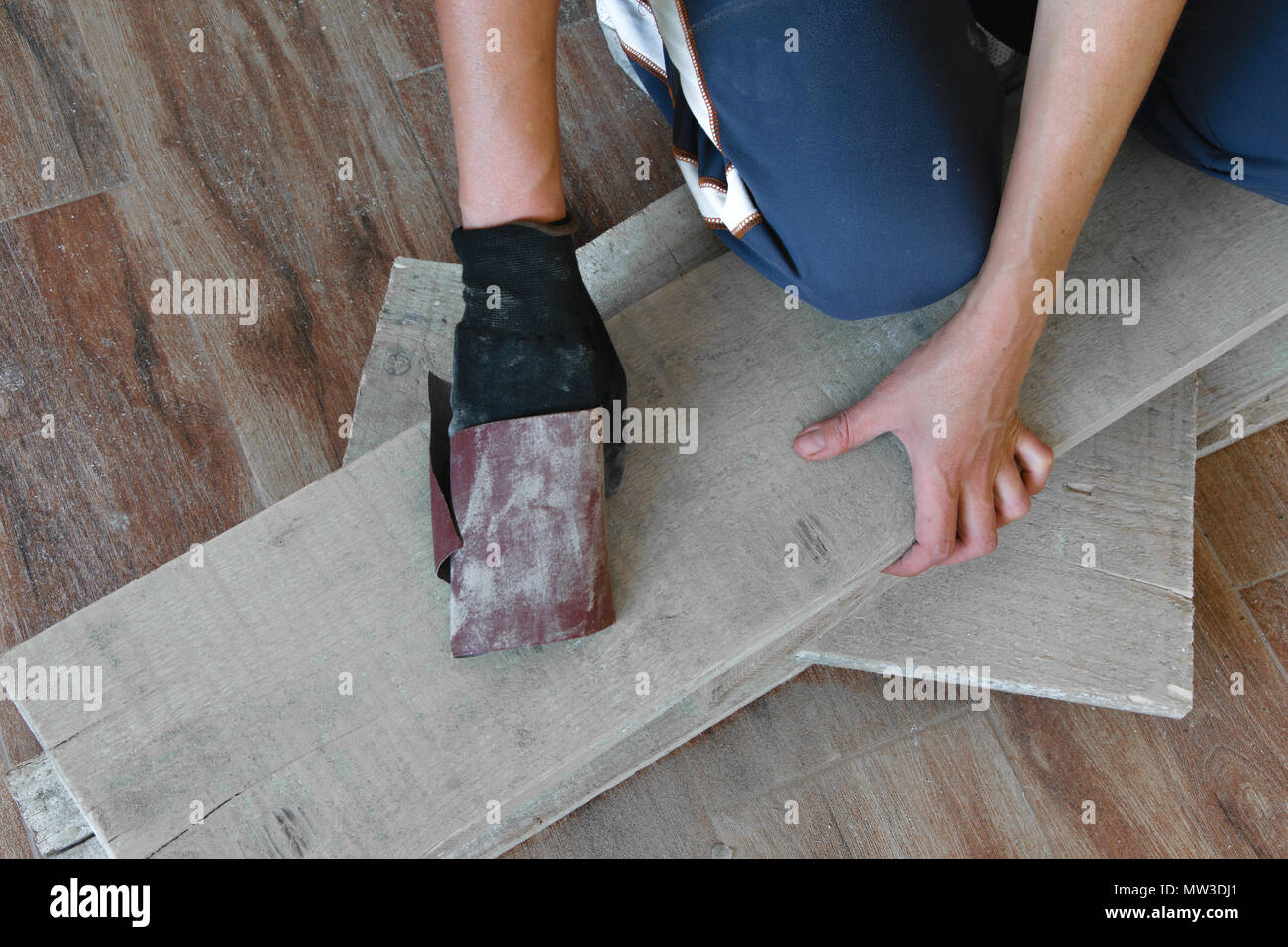 Femme sable avec du papier de verre fin une table en bois à l'intérieur. La réparation, bricolage concept Banque D'Images