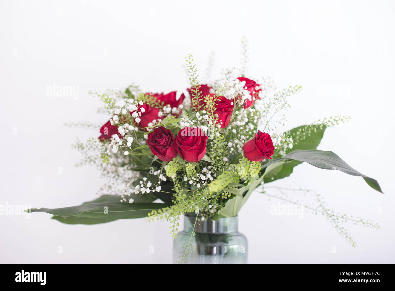 Bouquet de belles roses dans un vase avec des feuilles vertes et des fleurs blanches sur un fond blanc merci et de l'amour carte postale design concept fraîcheur Banque D'Images