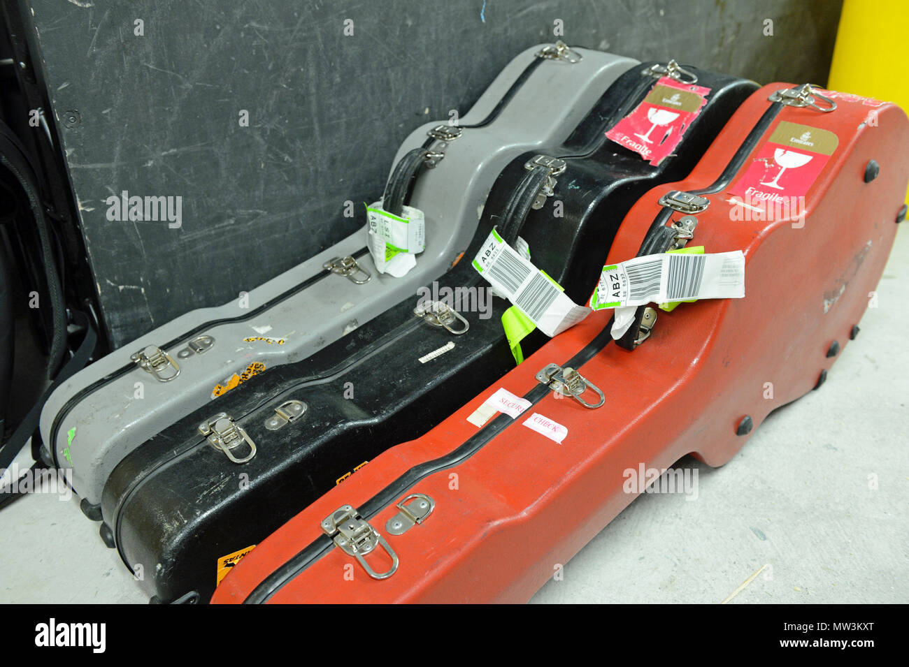 Sélection de différentes couleurs de guitare flight cases situées en coulisses lors d'un concert avec les étiquettes sur l'embarquement Banque D'Images