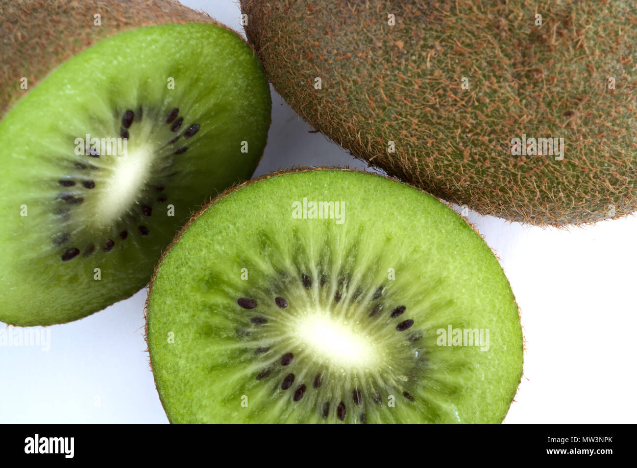 Kiwi vert coupé en deux à côté d'un ensemble isolé sur fond blanc Banque D'Images