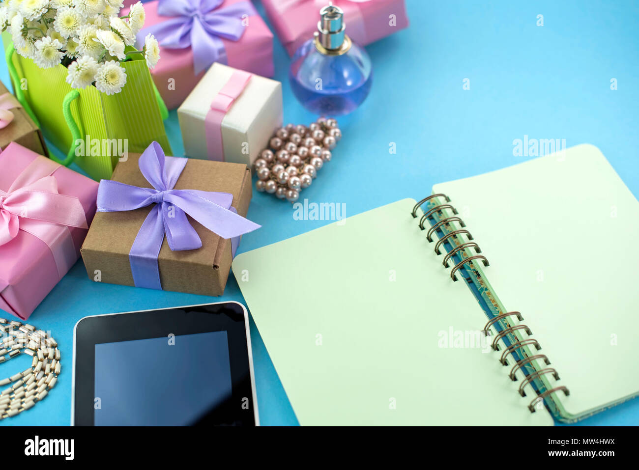 Arrière-plan de fête cadeau poster satin bouquet de fleurs perle bijoux smartphone tablette portable fond bleu. Vue d'en haut copie espace f Banque D'Images