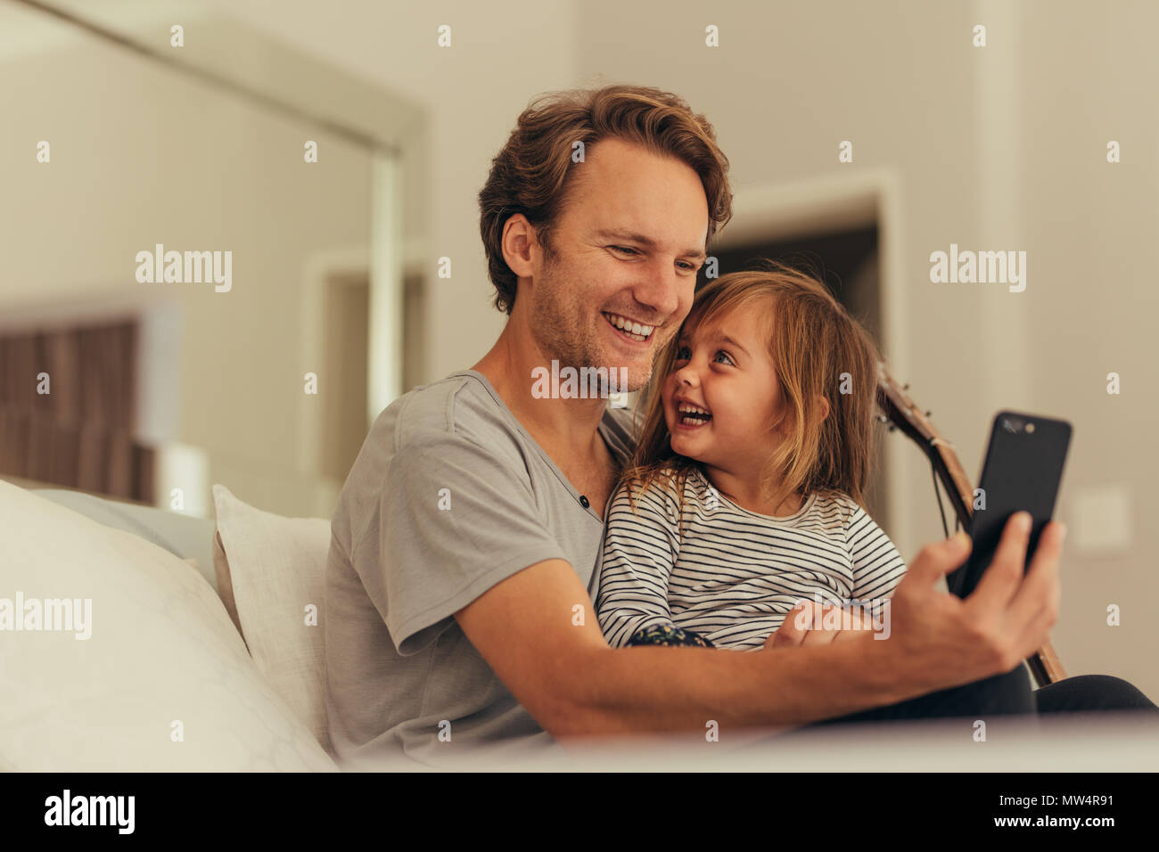 Homme assis avec sa fille à la maison et prendre une aide selfies téléphone mobile. Père et fille assis à la maison en prenant l'humeur ludique. selfies Banque D'Images