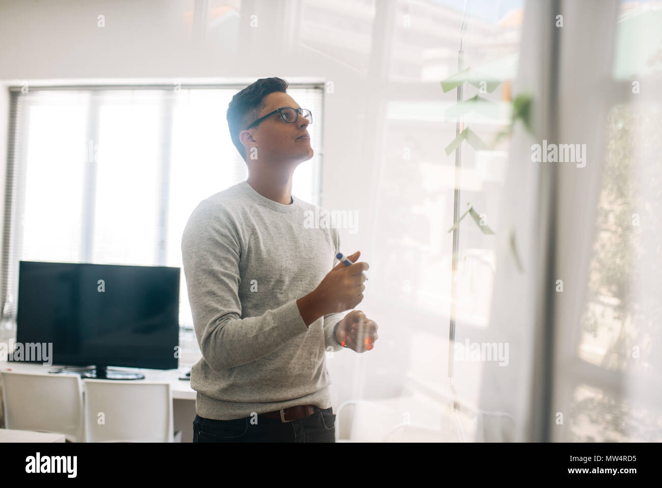 L'homme à l'aide de la planche tout en donnant une présentation en bureau. Développeur de l'application dans la salle du conseil d'administration, ayant écrit sur son post adhésif sur elle. Banque D'Images