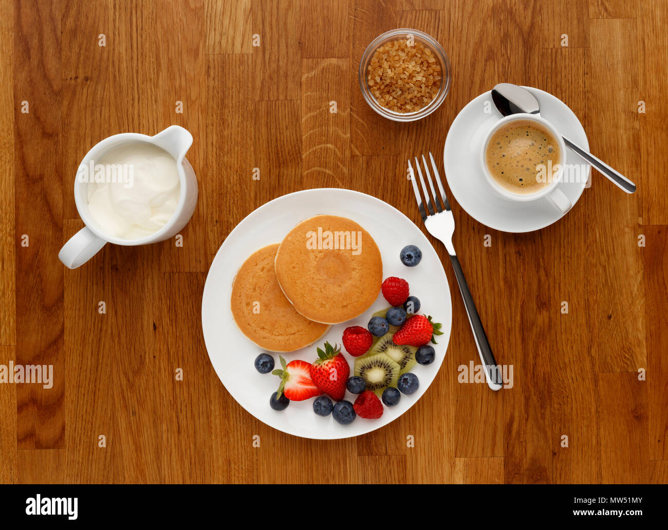 Petit déjeuner de crêpes, de fruits et du café, tourné sur une surface de travail de cuisine en bois, d'en haut. Banque D'Images