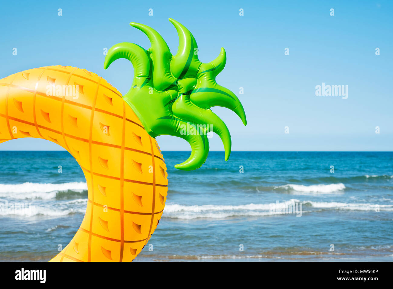 Libre de nager dans la forme d'un ananas sur la plage, avec l'océan et le ciel bleu en arrière-plan Banque D'Images