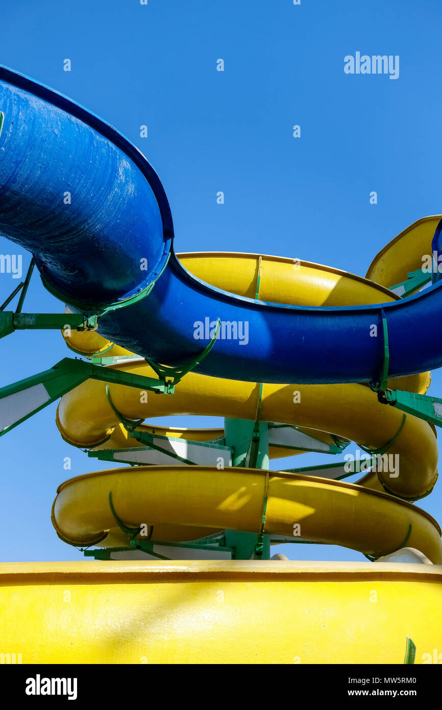 Fun d'été, parc aquatique. Parc aquatique moderne, jaune et bleu de diapositives. Journée ensoleillée, ciel bleu sans nuages, Close up, vu du dessous, POV. Banque D'Images