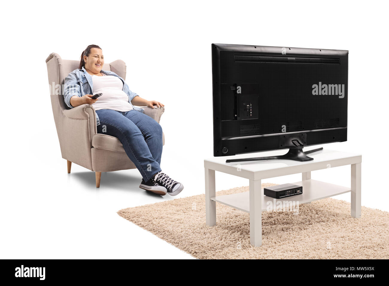 Jeune femme assise dans un fauteuil à regarder la télévision isolé sur fond blanc Banque D'Images