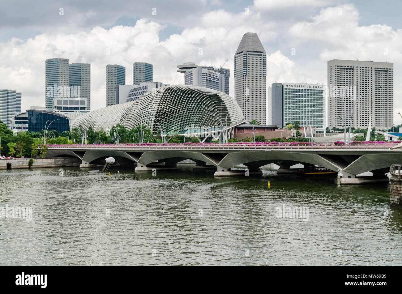 Un bateau de croisière connu comme twakows à travers la célèbre rivière Singapour. Le bâtiment à l'arrière est le fameux théâtre sur la baie, l'Esplanade. Banque D'Images