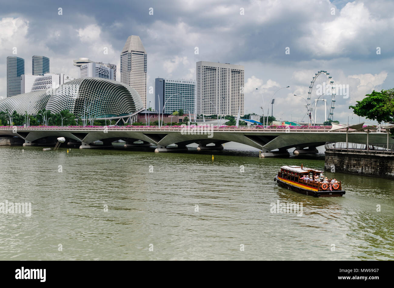 Un bateau de croisière et connu comme le twakows à travers la célèbre rivière Singapour. Le bâtiment à l'arrière est le fameux théâtre sur la baie, l'Esplanade. Banque D'Images