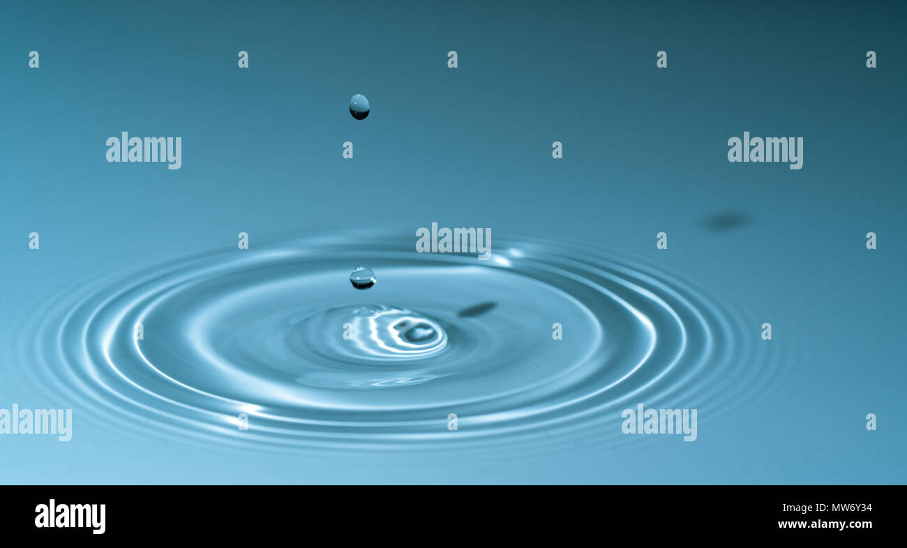 Splash goutte d'eau sur fond bleu Banque D'Images