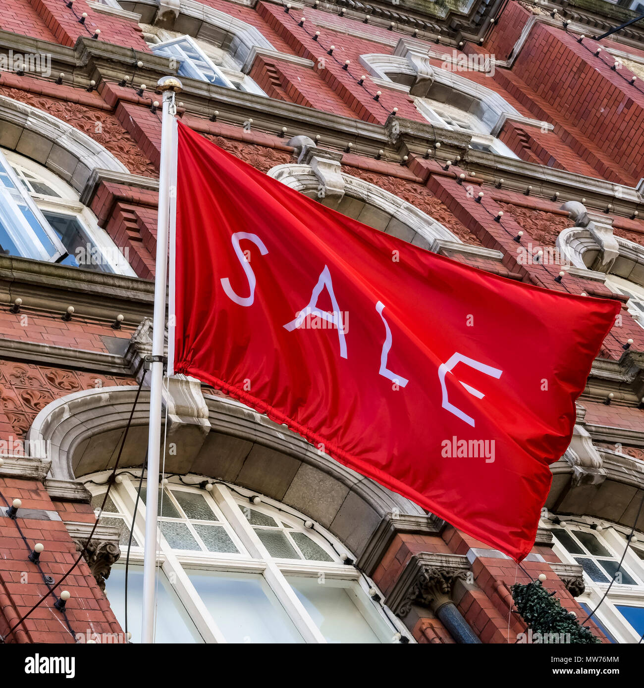 Shopping, vente drapeau rouge volant à Arnotts grand magasin, façade de bâtiment en grès brun, sur Henry Street. Dublin Irlande, Europe. Gros plan, vue en angle bas. Banque D'Images