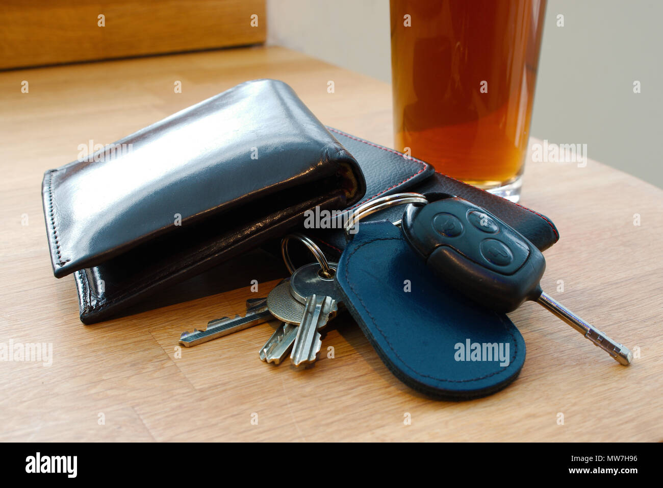 Porte-monnaie, clés de voiture, clés de maison et d'un téléphone mobile sur une table avec une boisson alcoolisée dans le contexte peut-être dans un pub ou bar Banque D'Images